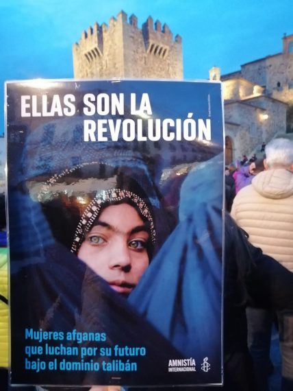 Pancarta con el lema "Ellas son la revolución" y una fotografía de una mujer afgana, en la Plaza Mayor de Cáceres