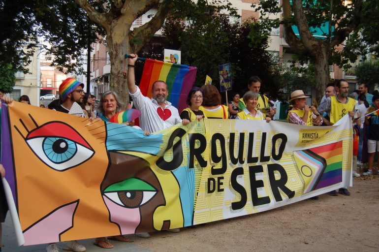 Activistas de AI Extremadura tras una pancarta con el lema ORGULLO DE SER