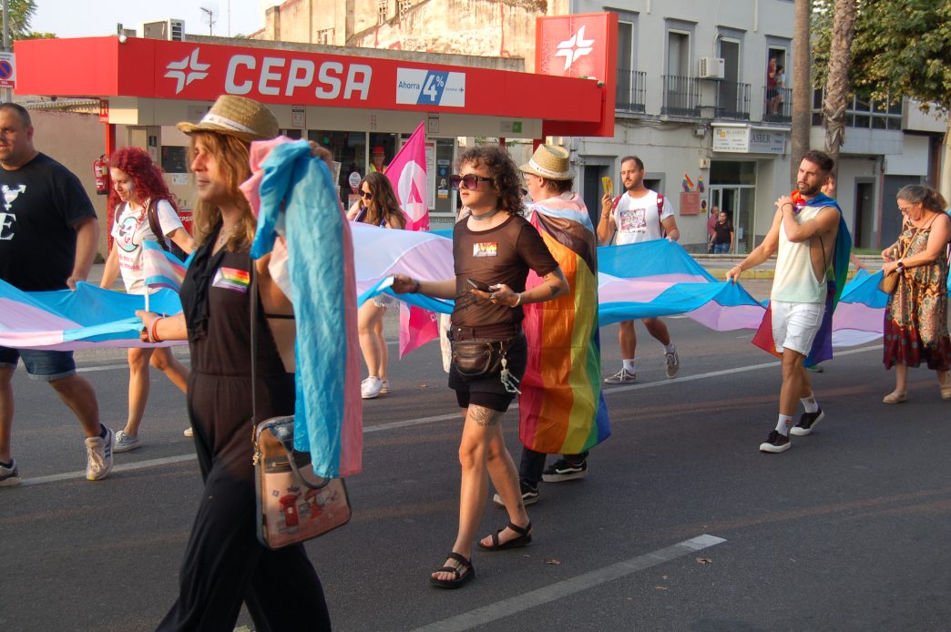 Un grupo de personas portan una bandera trans de varios metros de longitud