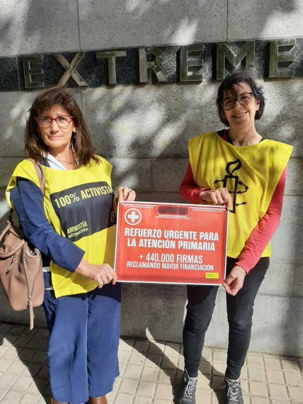 Dos activistas de Amnistía Internacional sosteniendo un cartel en el que se pide un refuerzo urgente para la atención primaria.