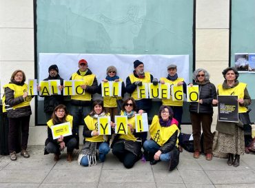 Activistas de Amnistía Internacional, la mayoría con petos amarillos con el logo de la ONG, portando cada uno una letra de forma que puede leerse ¡ALTO EL FUEGO YA!