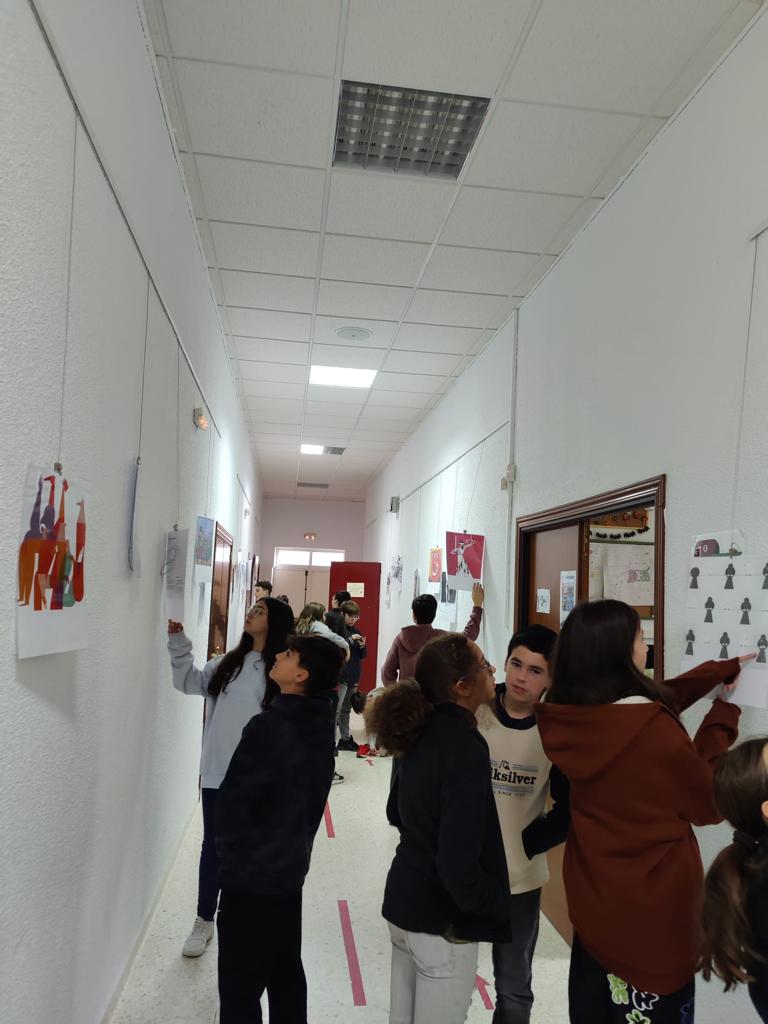 Alumnado del IES Bárbara de Braganza observando las obras que están colgadas en un pasillo.