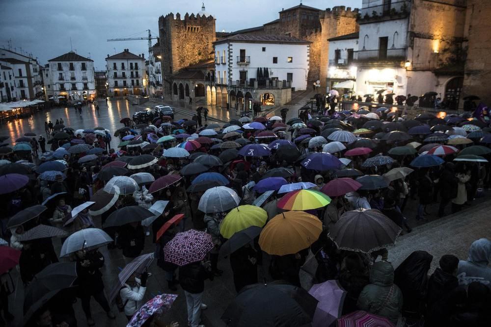 Una multitud de personas, protegidas por paraguas, en la Plaza Mayor de Cáceres.