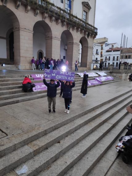 Varias pancartas en las escaleras que suben al Ayuntamiento de Cáceres en la Plaza de España. Dos niñas portan una pancarta con el lema QUE NO TE CORTEN LAS ALAS.