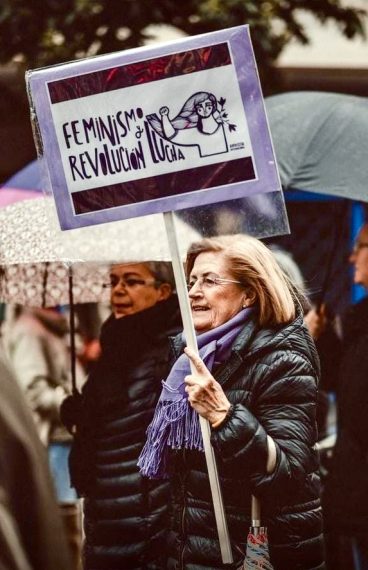 Activista de AI llevando una pancarta en la que se lee el lema FEMINISMO REVOLUCIÓN Y LUCHA, junto a la figura de una mujer con el puño en alto.