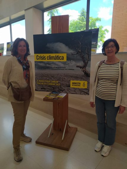 Dos activistas de Amnistía Internacional junto al cartel anunciador de la exposición.