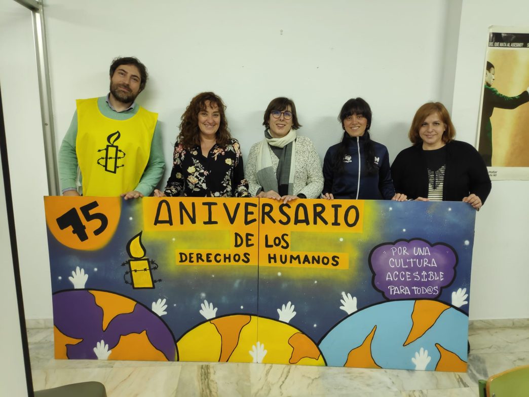 Un grupo de activistas de Amnistía Internacional sostiene un mural conmemorativo del 75 aniversario de los DD.HH.