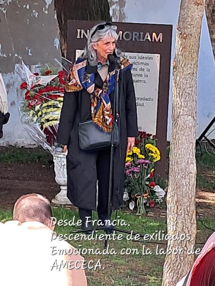 Una mujer en pie, ante el monumento a los represaliados. Abajo se lee el texto DESDE FRANCIA. DESCENDIENTE DE EXILIADOS EMOCIONADA CON LA LABOR DE AMECECA.