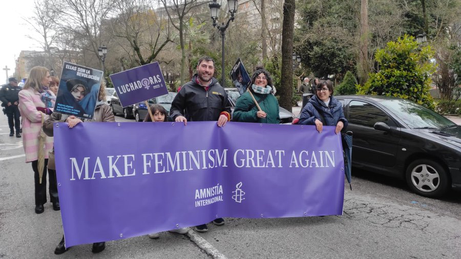 Grupo de activistas de AI en la marcha del 8 M en Cáceres, llevando una pancarta con el lema MAKE FEMINISM GREAT AGAIN.