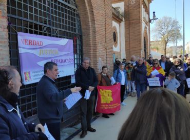 Un grupo numeroso de personas ante la antigua cárcel de Cáceres. Se ve una pancarta de AMECECA con el lema VERDAD, JUSTICIA, REPARACIÓN. También se ven otras pancartas, y una mujer cubierta con una bandera republicana.