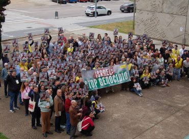 Un numeroso grupo de personas en la entrada del Palacio de Congresos de Mérida portando una pancarta con el lema ISRAEL: STOP GENOCIDIO y pequeños carteles con el mismo lema. Algunas llevan petos amarillos de Amnistía Internacional.