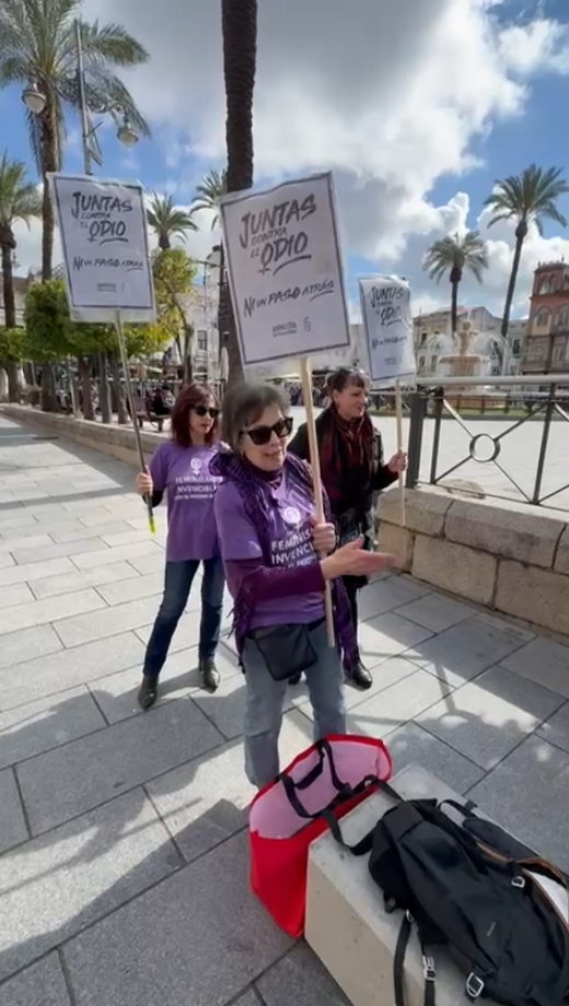 Tres activistas de AI en Mérida, con carteles con el lema JUNTAS CONTRA EL ODIO. NI UN PASO ATRAŚ.