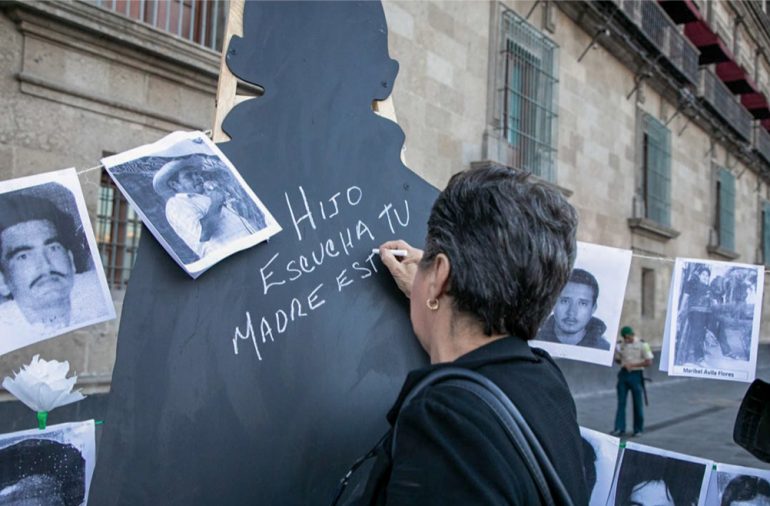 Una mujer mejicana está escribiendo en un cartel situado en la calle: "Hijo, escucha, tu madre está..."