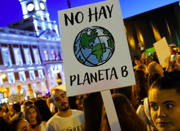 Una joven sostiene una pancarta que reza No hay planeta B en una manifestación en la Puerta del Sol