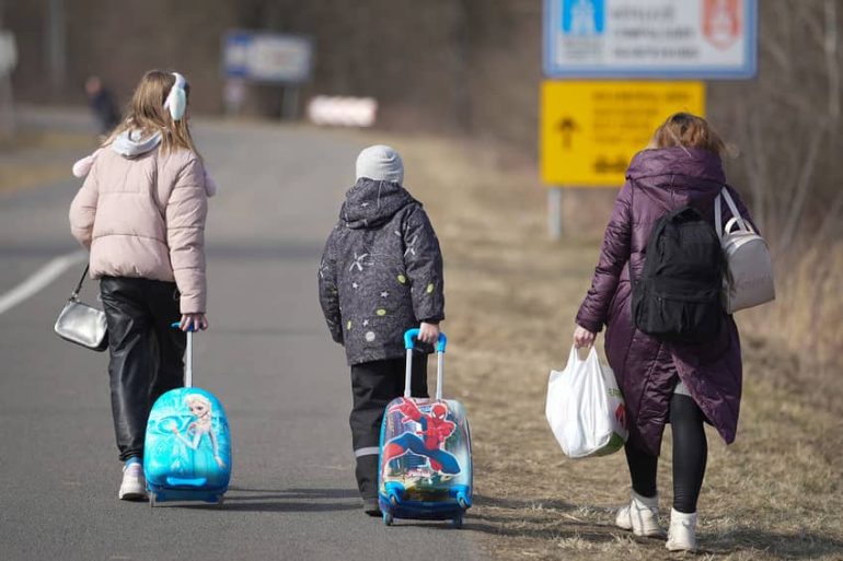 Una familia ucraniana camina por la carretera tras cruzar la frontera en la ciudad húngara de Lonya el 3 de marzo de 2022. Más de un millón de personas refugiadas ucranianas han huido a países vecinos como Hungría, formando largas colas en los pasos fronterizos tras la invasión rusa el 24 de febrero de 2022. © Christopher Furlong/Getty Images