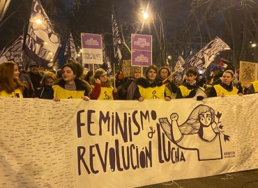 Pancarta Feminismo Revolución y Lucha sujeta por jóvenes activistas con peto de Amnistía Internacional en la manifestación del 8M