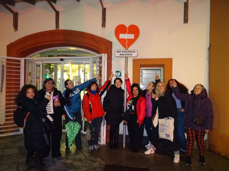 Algunas participantes del acto aparecen señalando una señal de tráfico de dirección prohibida con forma de corazón en la que aparece la leyenda No a la Violencia Machista